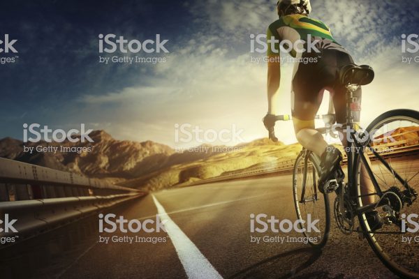 Cyclist riding a bike to the sunset on the highway